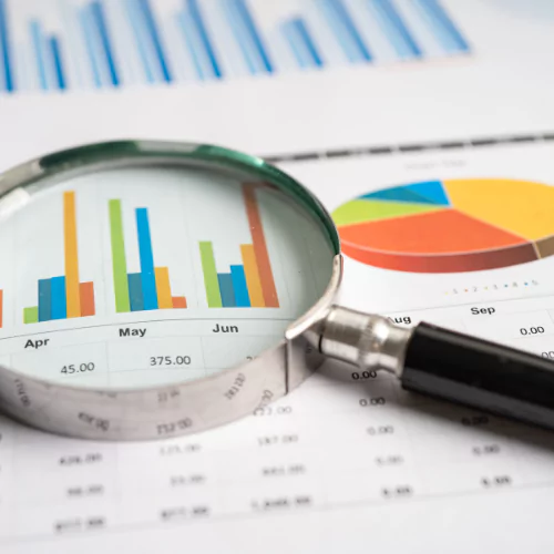 Magnifying glass analyzing business charts and financial graphs on a report