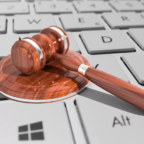 Wooden judge's gavel resting on a keyboard, symbolizing online legal databases and digital law research.