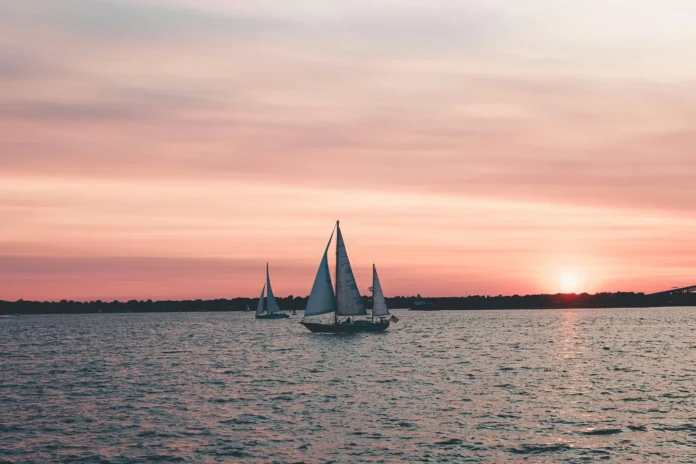 Sailboats on Narragansett Bay at sunset, representing Rhode Island’s coastal business environment.