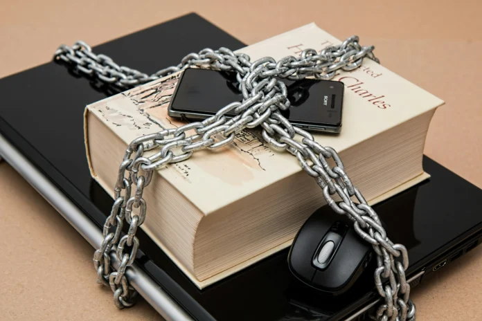 Equifax data breach settlement illustration with chained laptop and book