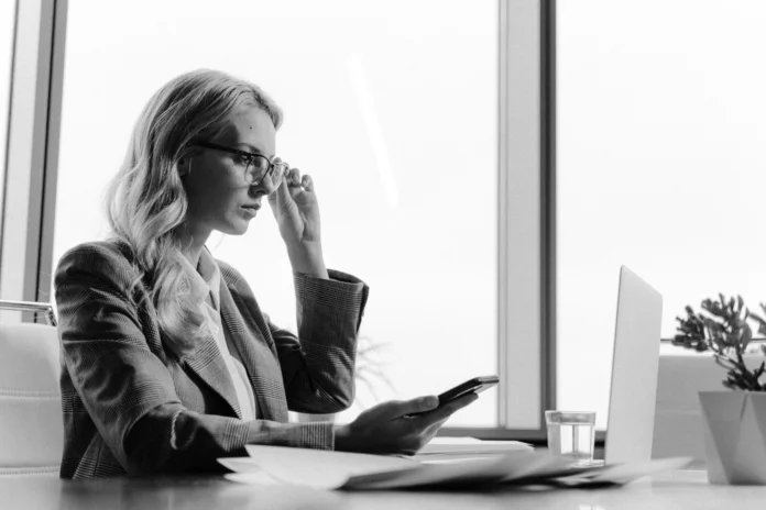 Professional woman using laptop and phone while conducting a Massachusetts Business Entity Search in an office