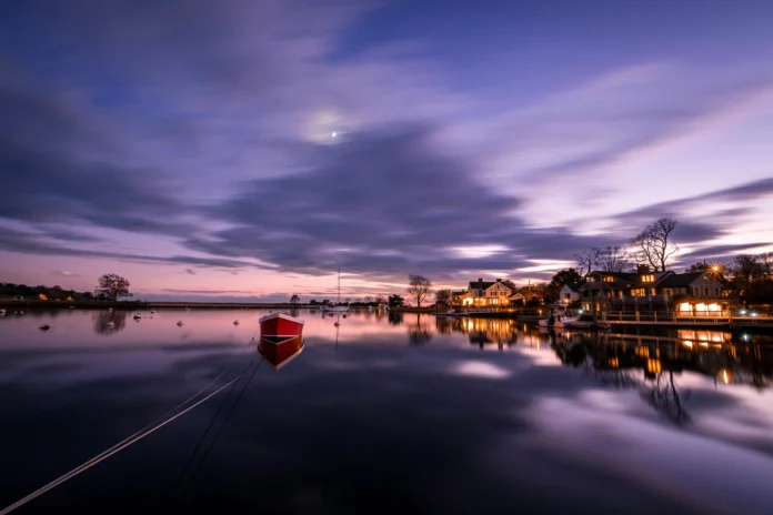 Evening harbor scene in coastal Connecticut with moored boat and shoreline homes — symbolic illustration for the Connecticut Business Entity Search.