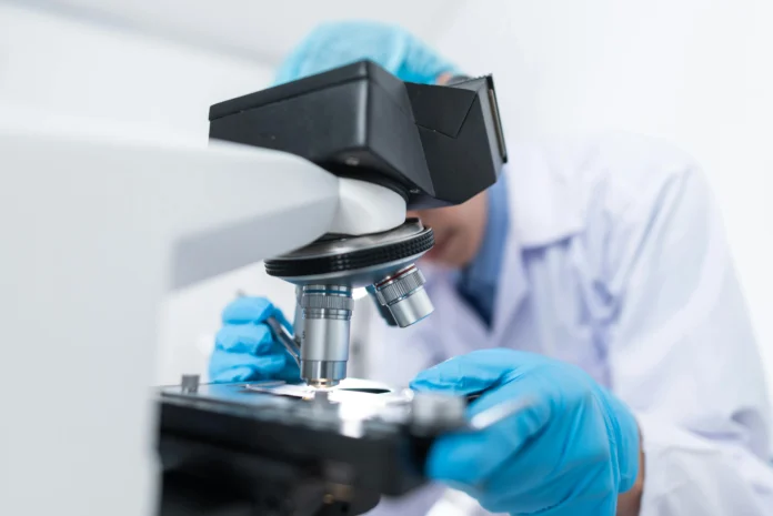 Researcher examining protein samples under a microscope, representing the Localizatome database focus on protein localization in human cells.