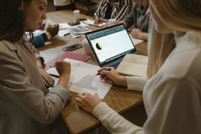 Team reviewing business data and filings on a laptop and printouts, representing use of the North Dakota Business Entity Search.
