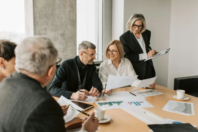 Business professionals reviewing documents and charts in a meeting, illustrating the use of the Wyoming Business Entity Search for verification.
