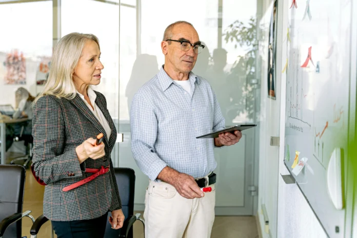 Two professionals reviewing charts on a whiteboard while discussing data, illustrating real-world use of the Virginia Business Entity Search.