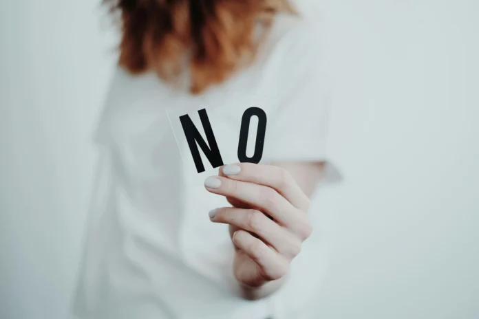 A person holding a paper with the word NO, symbolizing resistance against human trafficking — GRETA Human Trafficking Database.